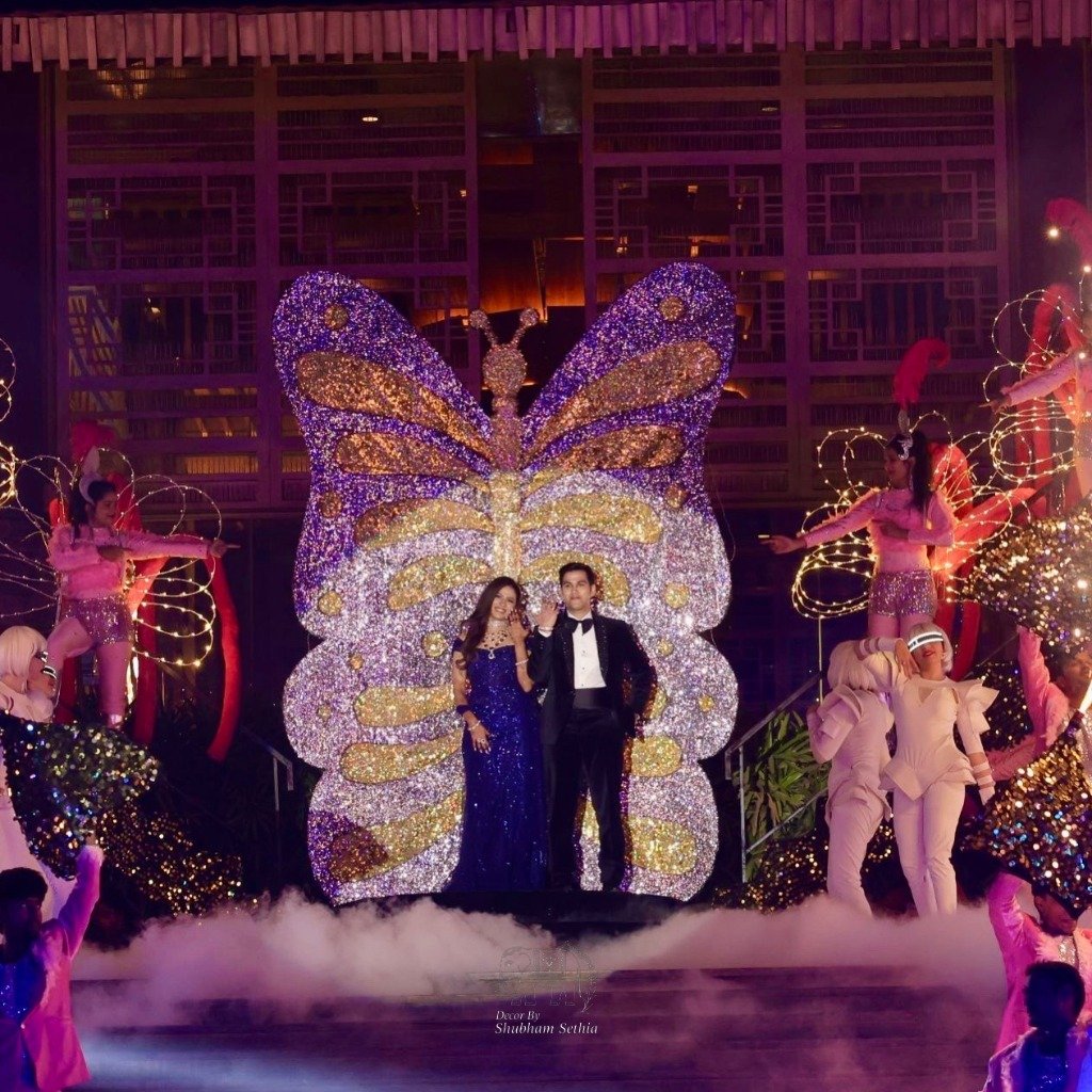 Spectacular butterfly stage installation by Decor by Shubham — couple standing before giant illuminated butterfly sculpture